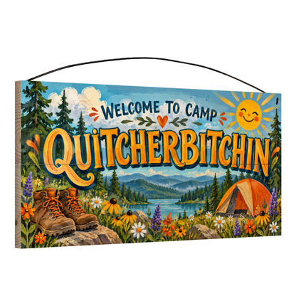 Angled view of Welcome to Camp Quitcherbitchin Hiking Boots wood sign, 7 × 14 in, showing board thickness and wire hanger