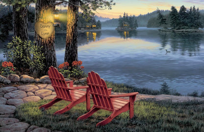 This romantic custom couple print features a lakeside at sunset, with glowing cabins across the water and a tree in the foreground personalized with two names carved into a heart.