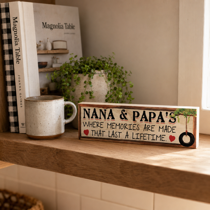 Twelve-inch Nana and Papa maple sign standing on a sunny kitchen shelf beside a mug, cookbook, and plant.